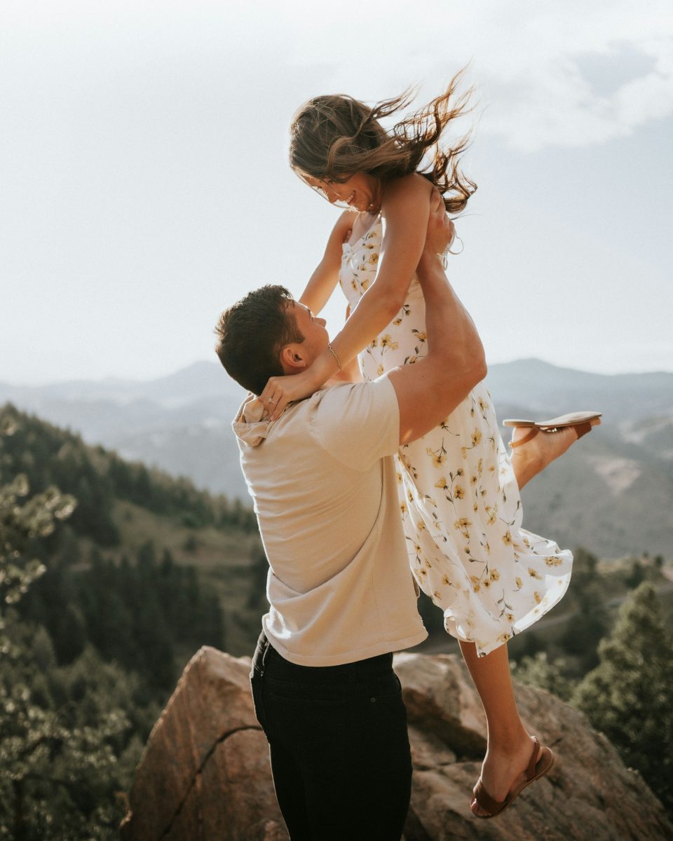 Man holding woman up against mountain backdrop - How to manifest love